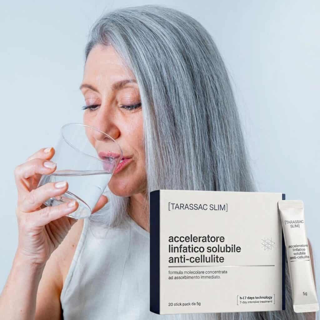 Donna anziana con capelli grigi che sorseggia acqua in un bicchiere.