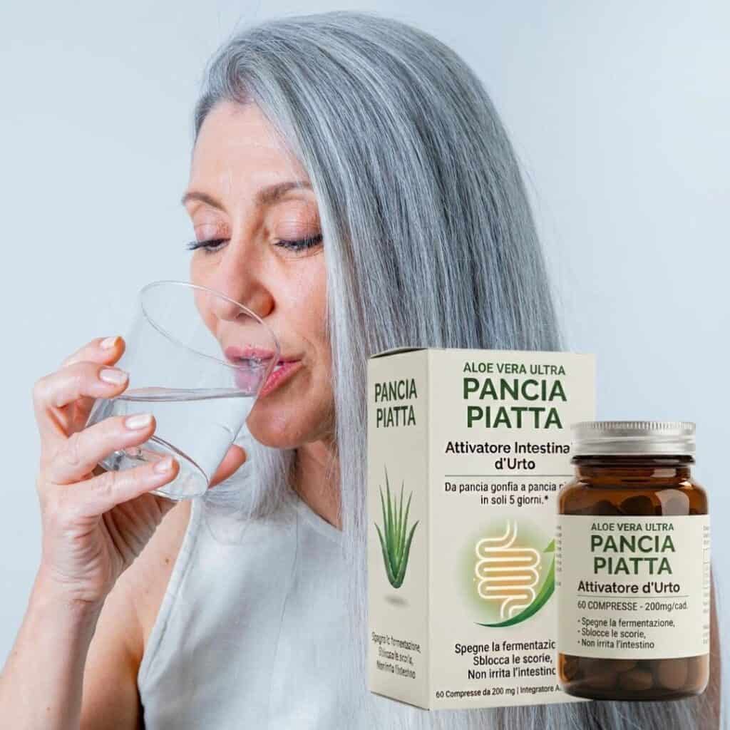 Donna con capelli grigi beve acqua accanto a integratore Pancia Piatta Aloe Vera.